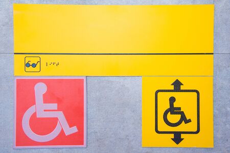 Disabled help call button. Yellow plate with the image of a disabled person and a call button. The complexity of restricting human movement.の写真素材