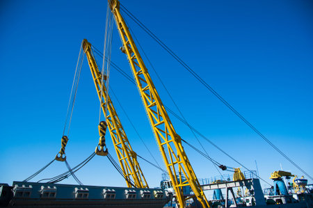 Loading in port. Floating port crane on blue sky background. Chains and hooks hoist with slings for...