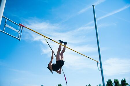 Competition pole vault jumper female on blue sky backgroundの写真素材