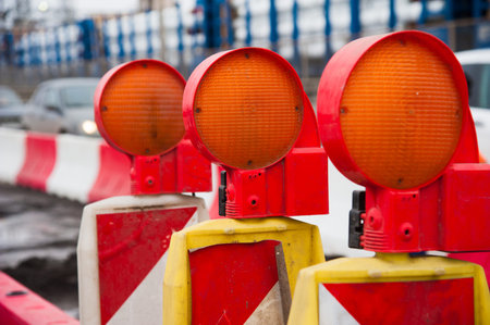 Repair of asphalt pavement. Orange construction light on barricade and red safety barriers on the...
