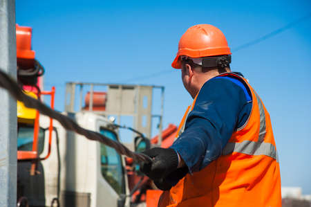 Electricians repairing wire of the power line on electric power poleの写真素材