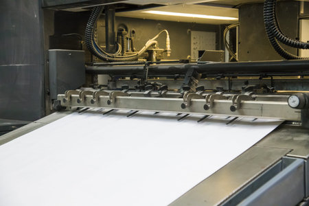 Printing presses at work in the printing. Printed sheets of paper are served in the printing press