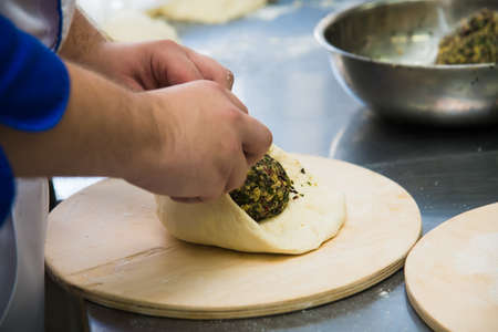 Professional chef prepares a closed meat pie in the restaurant kitchenの写真素材