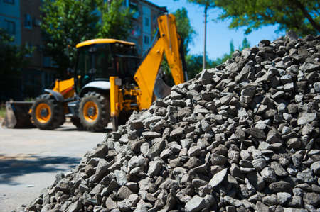 Repair of the old and construction of a new asphalt road. The excavators, graders and road rollers working on the new road construction site.の写真素材
