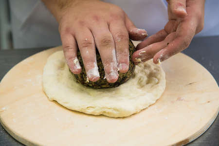 Professional chef prepares a closed meat pie in the restaurant kitchenの写真素材