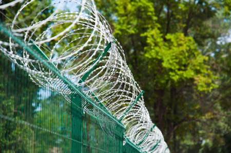 Barbed wire fence stretched around prison wallsの写真素材