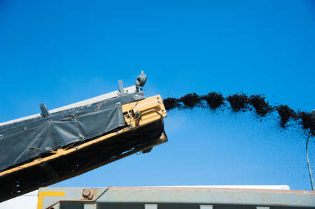 Repair of asphalt pavement of the road. Road cold milling machine removes the old asphalt and loading into a dump truckの写真素材