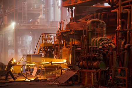 Metal structures and buildings of the old metallurgical plant inside and outside. The process of melting metal. Steelworker at work. Products of the metallurgical enterprise.の写真素材