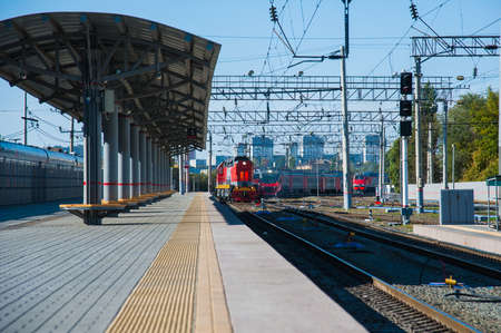 Red train locomotive on rail tracks and railway platform. Train and railway station.の写真素材