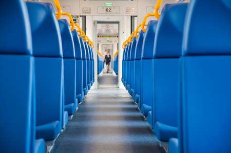 Inside of a train cabin with blue seats and sunlight coming in through the windowsの写真素材