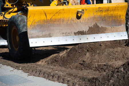 Repair of the old and construction of a new asphalt road. The excavators, graders and road rollers working on the new road construction site.の写真素材