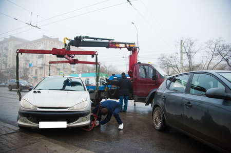 Traffic police officers on the street lifting the car on the tow truck for taking awayの写真素材