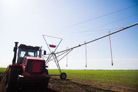 Automated farming irrigation sprinklers system on cultivated agricultural landscape fieldの写真素材