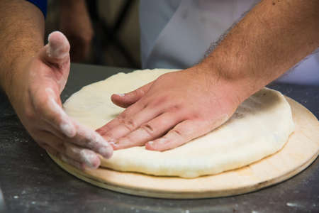 Professional chef prepares a closed meat pie in the restaurant kitchenの写真素材