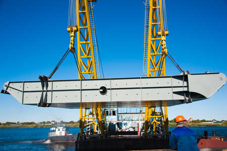 Loading in port. Floating port crane on blue sky background. Chains and hooks hoist with slings for loading in the port close-upの写真素材