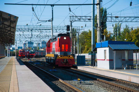 Red train locomotive on rail tracks and railway platform. Train and railway station.の写真素材