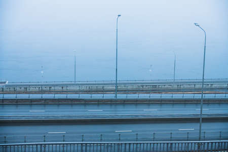 Autumn city landscape. Embankment and city road near the river in heavy fogの写真素材