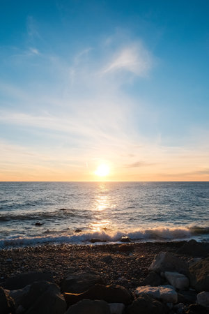 Seascape. Wild pebble beach at sunset. Sea wave is breaking on the shoreの写真素材