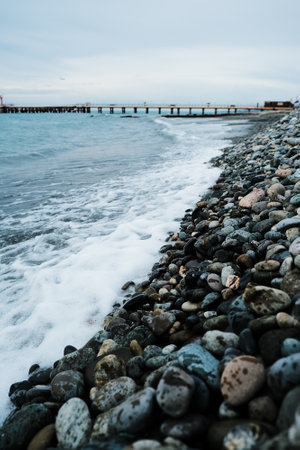 Seascape. Wild pebble beach at sunset. Sea wave is breaking on the shoreの写真素材