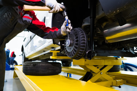 Auto mechanic working at auto repair shop. Repair of the rear brake drumの写真素材
