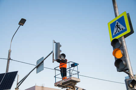 Worker on the lift sets and adjusts the traffic light at the pedestrian crossing. Traffic light and road sign Pedestrian crossingの写真素材