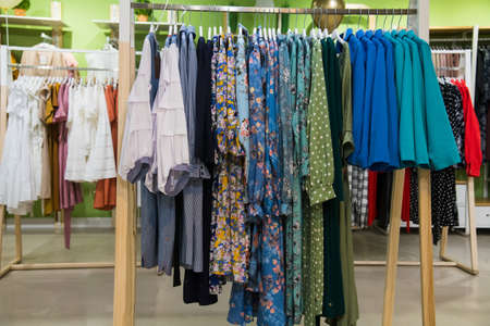 Colorful women's dresses on hangers in a retail shopの写真素材