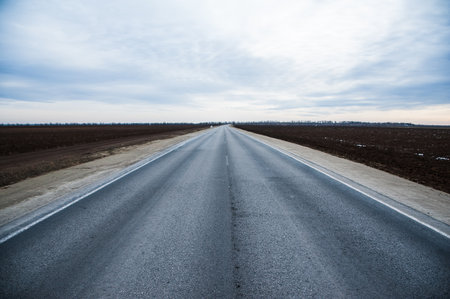 Dry and smooth asphalt road stretching under a cloudy skyの写真素材