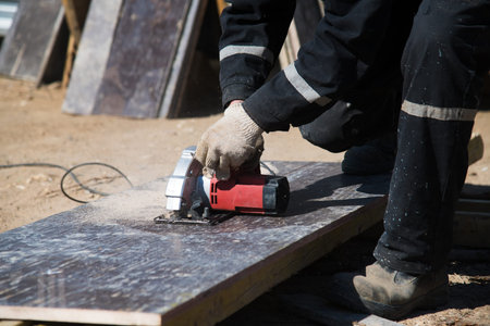 The builder uses an electric grinding machine to cut the profiled flooring