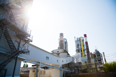 Plant for the production of cement and building mixes. Factory structures, pipes against the blue skyの写真素材