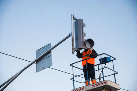 Worker on the lift sets and adjusts the traffic light at the pedestrian crossing. Traffic light and road sign Pedestrian crossingの写真素材