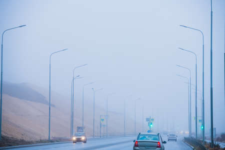 Autumn city landscape. Embankment and city road near the river in heavy fogの写真素材