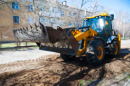 Repair of the old and construction of a new asphalt road. The excavators, graders and road rollers working on the new road construction site.の写真素材