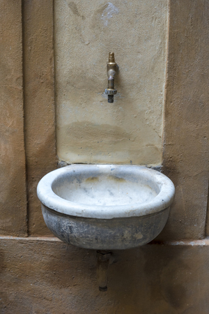 Old wash basin on the wall of a house, rusty and not working.の写真素材