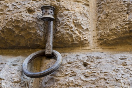 Old wall with a wrought-iron ring beneath the torch.の写真素材