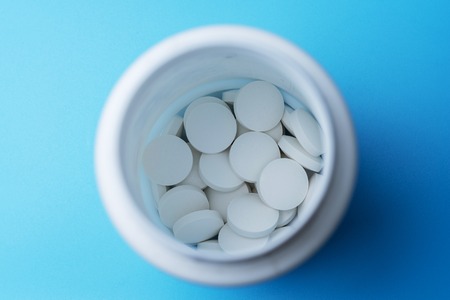 Pills in the bottle, top view on blue background.の写真素材