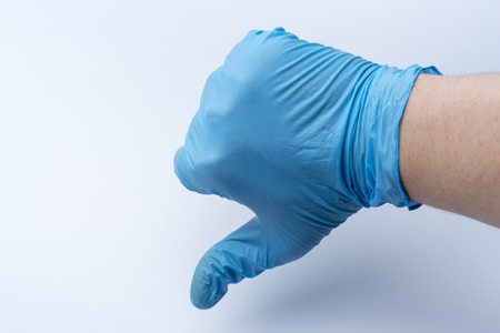 A hand in a blue glove shows a thumbs down.の写真素材