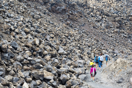 People walk along the volcanic rocks on the island of Santorini.のeditorial素材