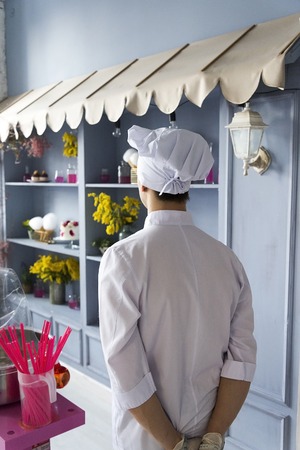 Rear view of the chef in the kitchen in the restaurant. In a white robe and a cap.の写真素材