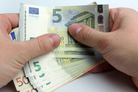 Hands holding a wad of cash on a white background.
