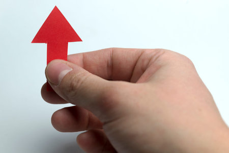 Hands holding red arrow up on a white background.の写真素材