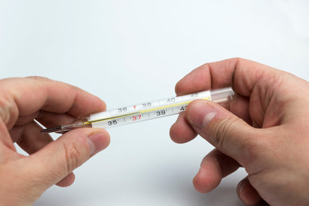 Hand holds a thermometer on a white background.