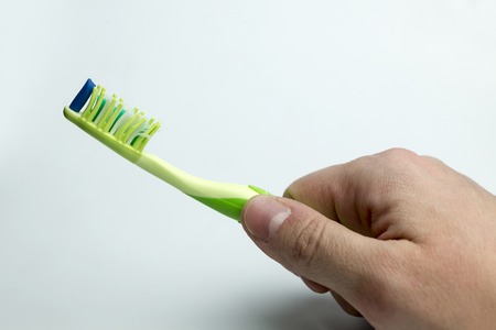 Hand holds a toothbrush on a white background.の写真素材