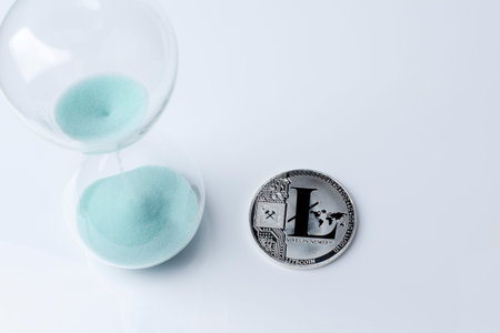 Silver bitcoin and hourglass on a white background. Digital currency.