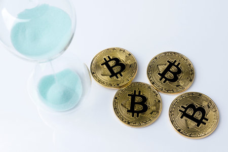 Gold bitcoin and hourglass on a white background.