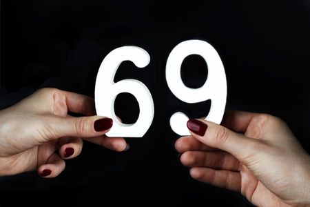 On a black background, female hand with number sixty-nine.の写真素材