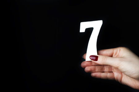 On a black background, female hand with number seven.の写真素材