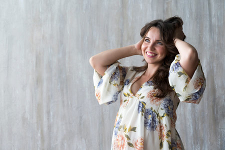 Pregnant girl in dress on grey wall background in Studio.