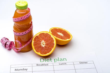 Diet plan and bottle of grapefruit juice with fresh grapefruit on white background. The concept of healthy eating.の写真素材