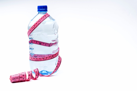 plastic water bottle and measuring tape isolated on white. The concept of health.の写真素材