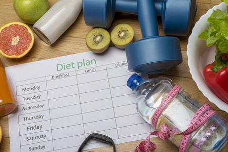 Diet plan, menu or program, roulette, water, dumbbells and diet food with fresh fruit on wooden floor. Weight loss and detoxification concept, top viewの写真素材